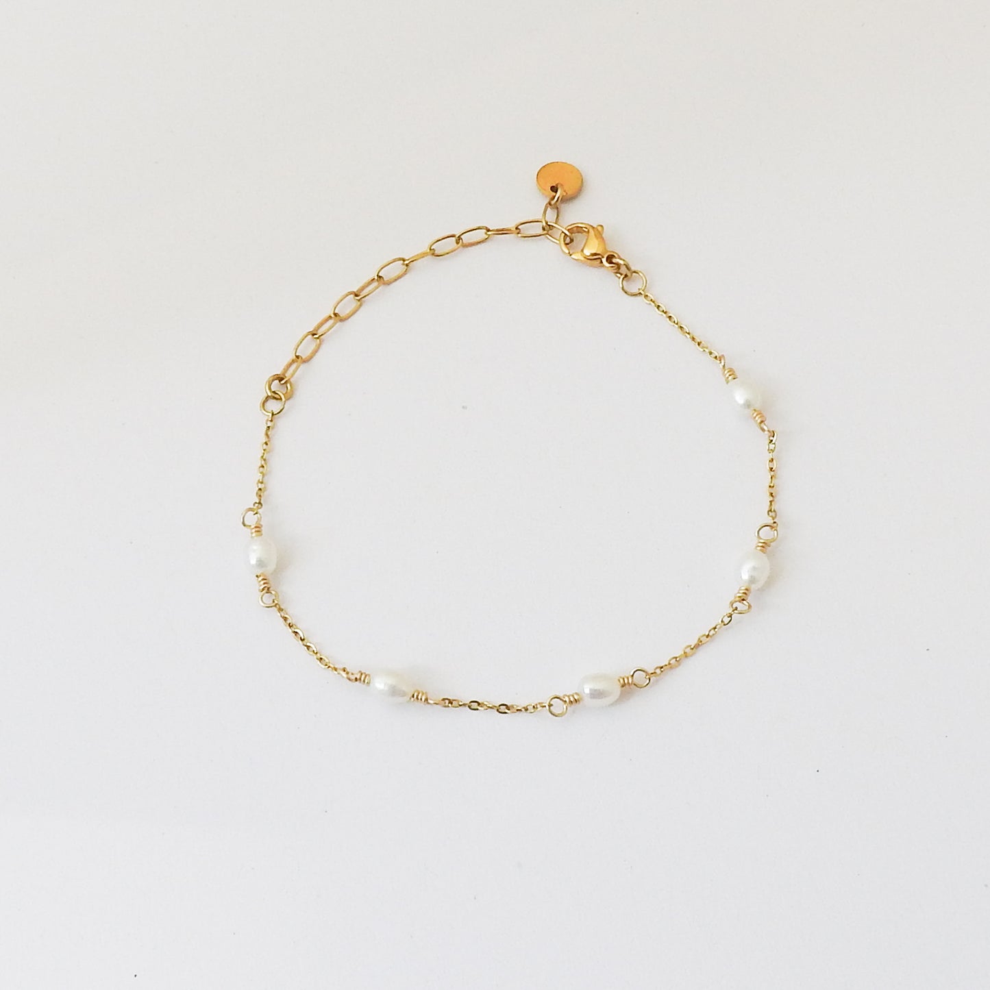 A delicate gold chain bracelet with irregular white pearl beads spaced along the chain, displayed on a clean white background.