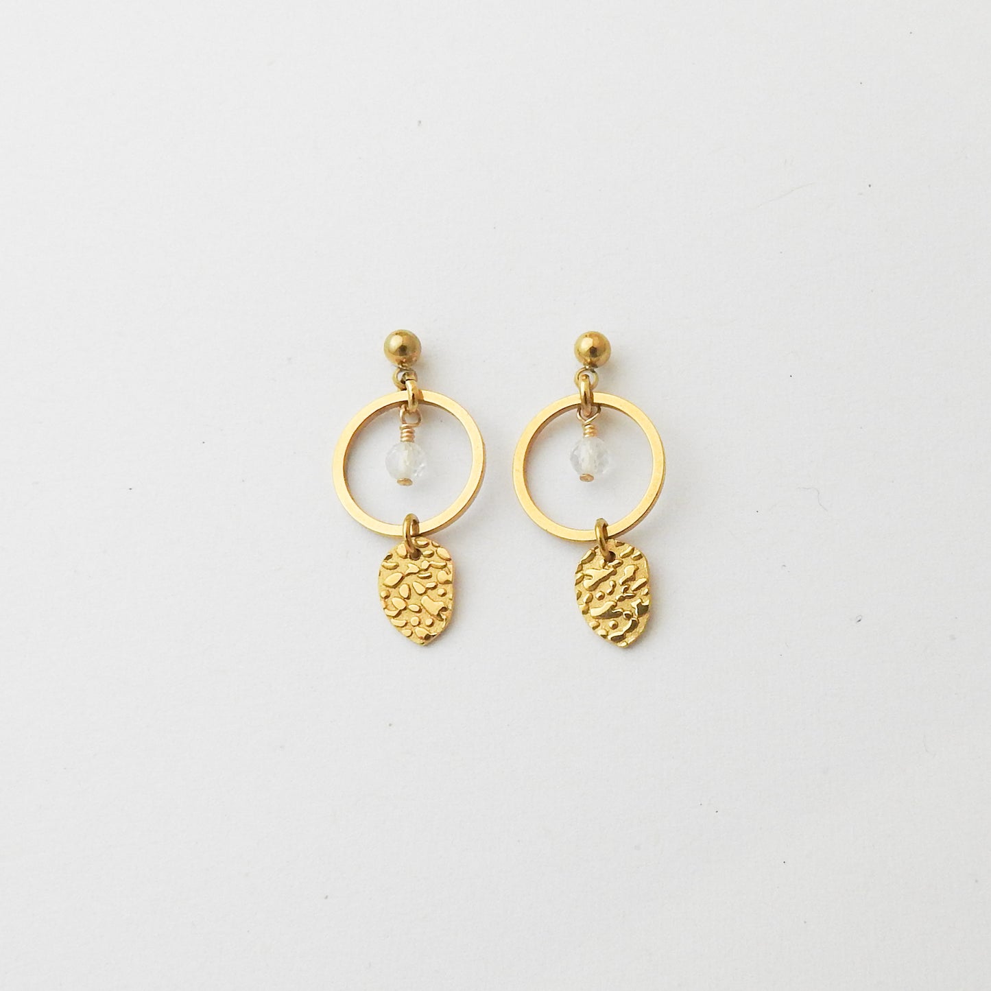 A pair of gold-toned dangle earrings featuring a circular hoop, a small clear faceted bead, and a textured pinecone-shaped charm, displayed on a clean white background.