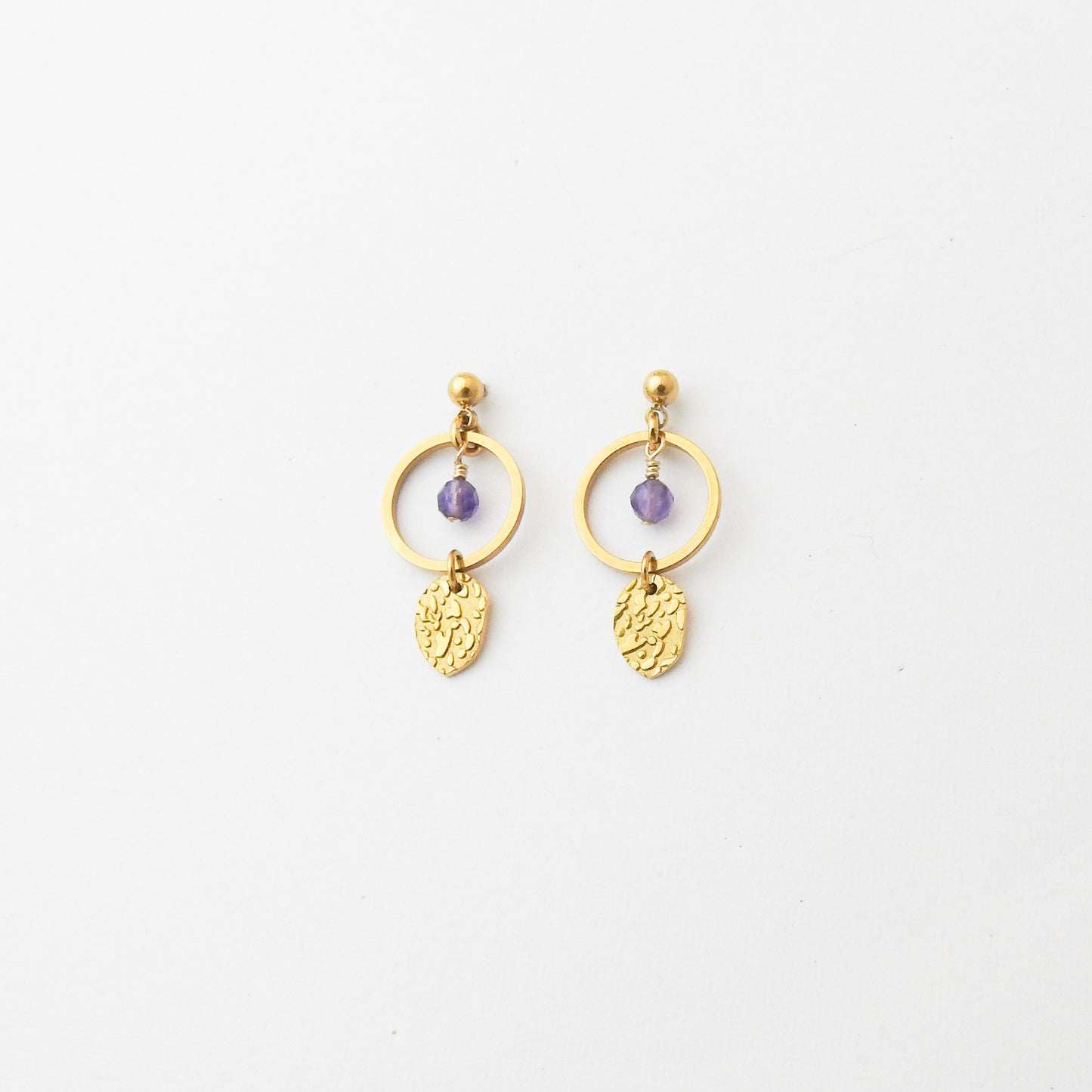 A pair of gold dangle earrings with a small purple bead and textured gold leaf charms, displayed on a clean white background.