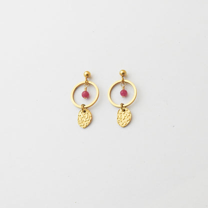 A pair of gold-toned dangle earrings with a circular hoop, a small pink bead, and a textured leaf-shaped charm, displayed on a clean white background.