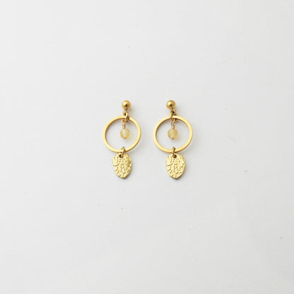 A pair of gold dangle earrings featuring a circular hoop, a small bead, a tiny clear stone, and an engraved leaf-shaped charm, displayed on a clean white background.