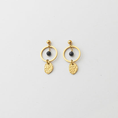 A pair of gold dangle earrings featuring a thin circular hoop, a small black bead, and a textured leaf-shaped charm, displayed on a clean white background.