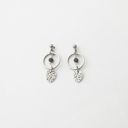 A pair of silver dangle earrings featuring a circular hoop, a small dark bead, and a textured leaf-shaped charm, displayed on a clean white background.