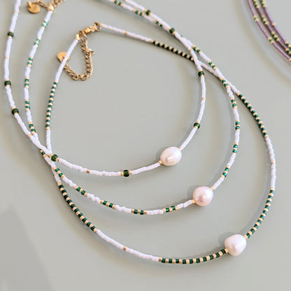 Set of layered necklaces with beads and pearls on a light gray background