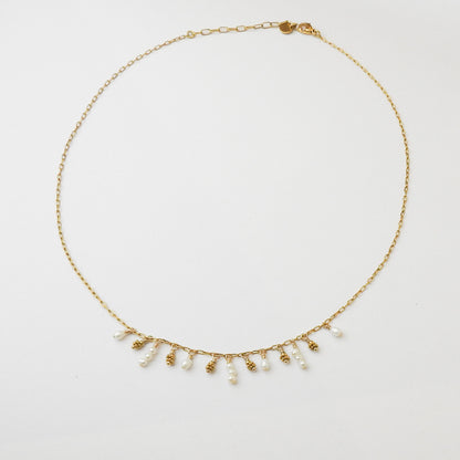 A delicate gold chain necklace featuring a fringe of small white freshwater pearls and textured gold bead drops, displayed on a clean white background.