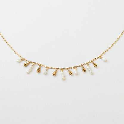 A delicate gold chain necklace featuring small dangling pearl beads and textured gold bead accents, displayed against a clean white background.