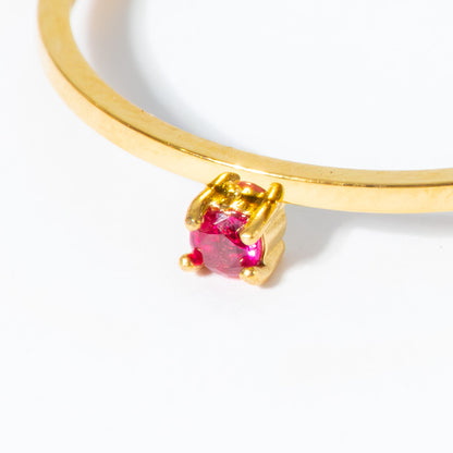 A close-up of a gold ring with a single round-cut pink gemstone in a prong setting, shown against a plain white background.
