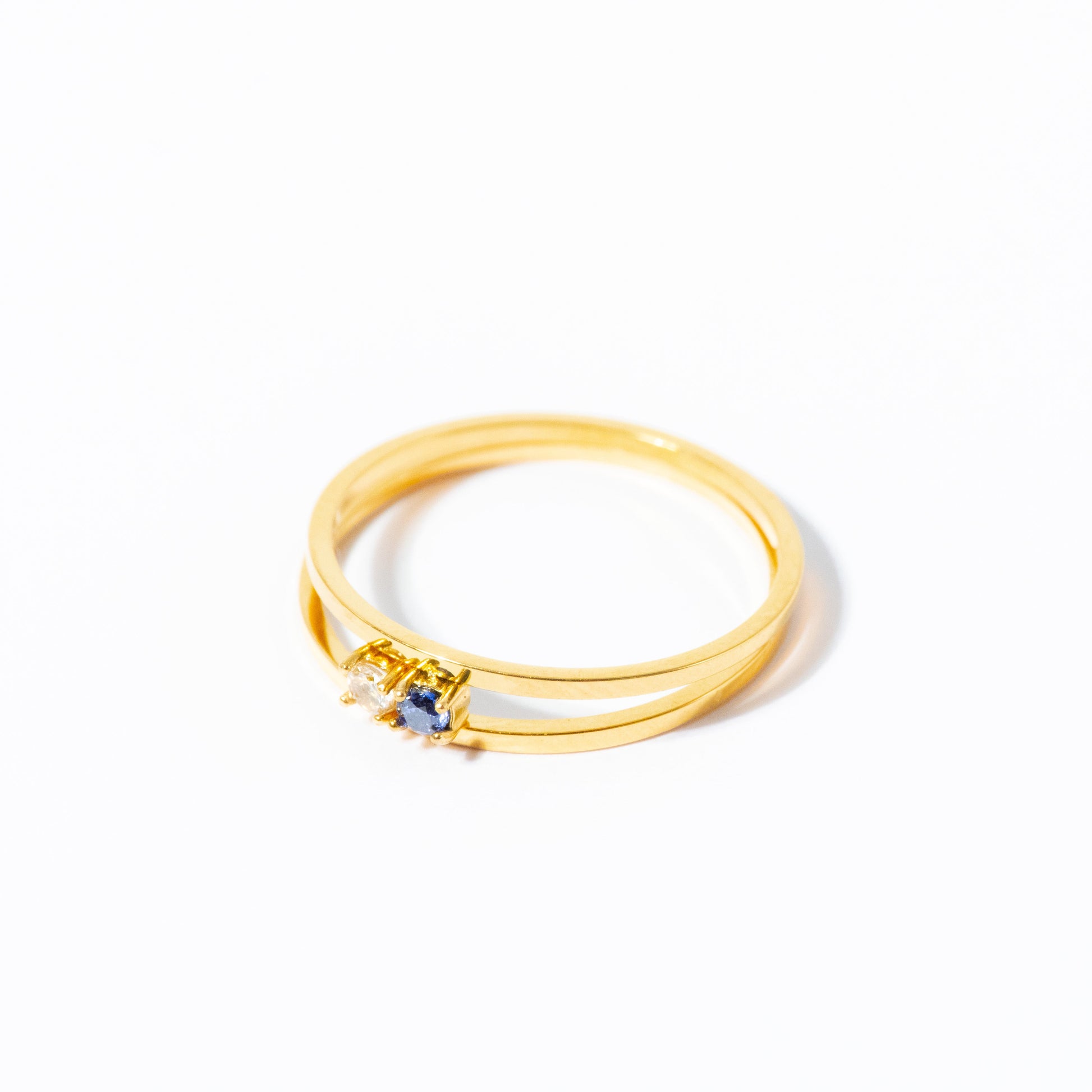 A gold ring with a double-band design and a small central cluster of clear stones, photographed on a clean white background.