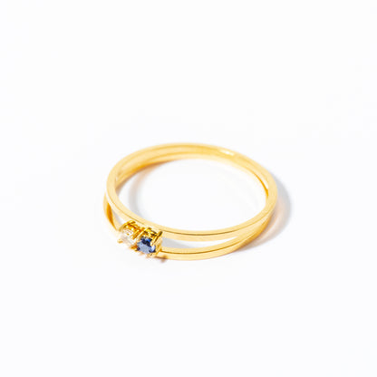 A gold ring with a double-band design and a small central cluster of clear stones, photographed on a clean white background.