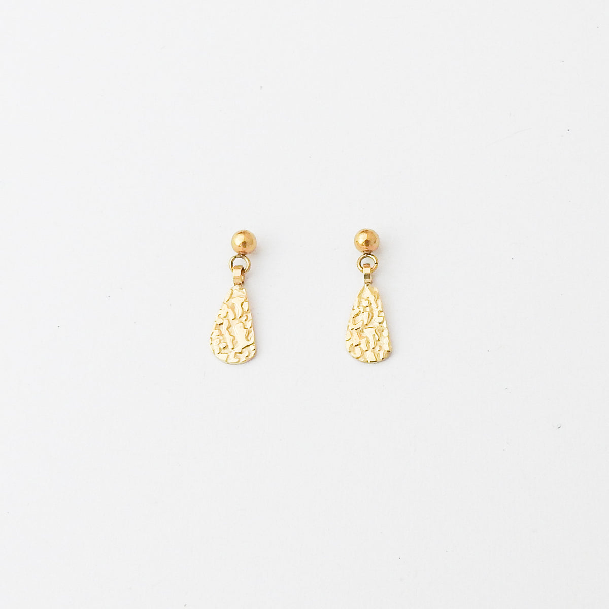 A pair of gold dangle earrings with textured teardrop-shaped charms and small round gold studs, displayed on a clean white background.