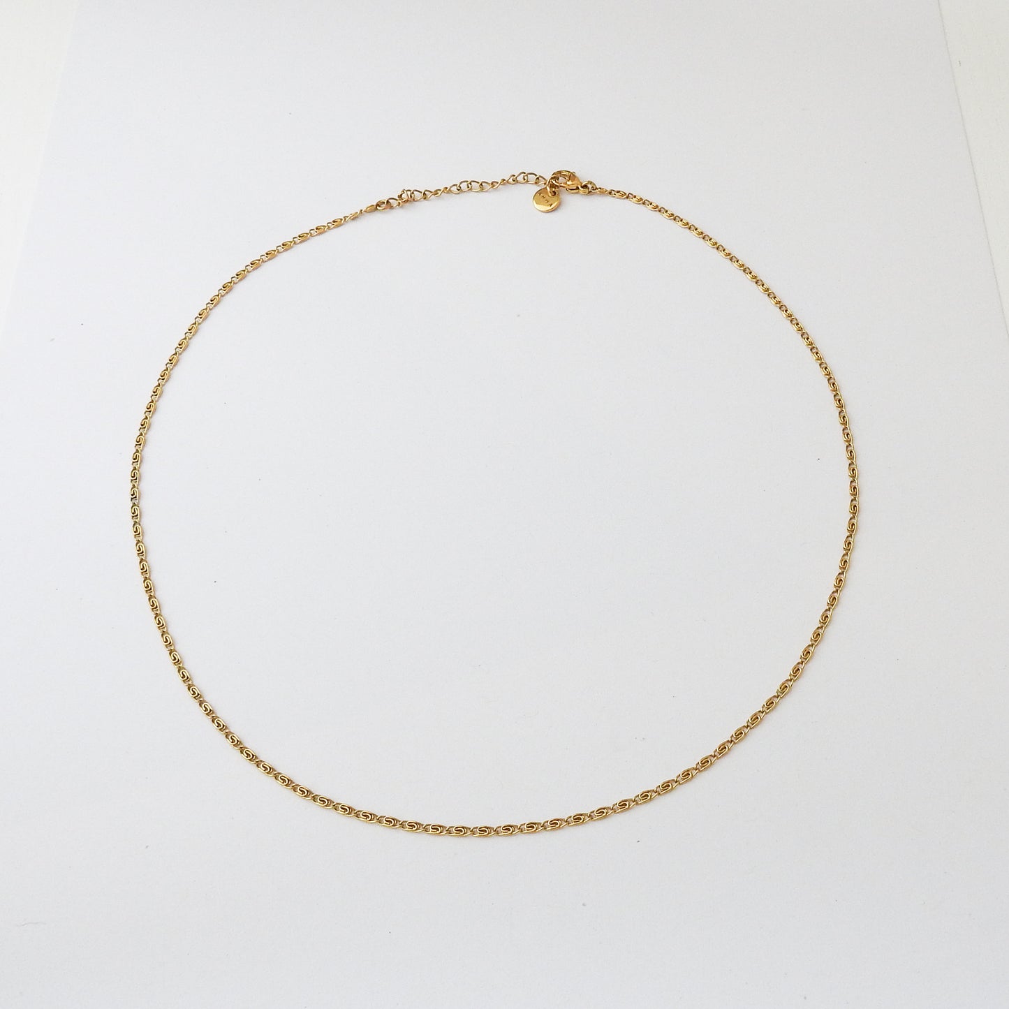 A delicate gold chain necklace with a small heart charm, displayed on a clean white background.