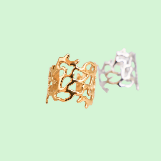 Gold and silver coral-shaped rings on a light green background