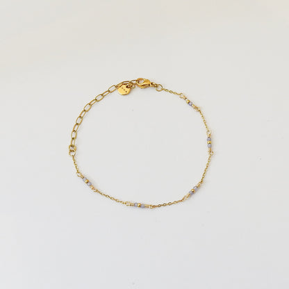 A delicate gold chain bracelet with small light blue faceted beads spaced along the band, displayed on a clean white background.