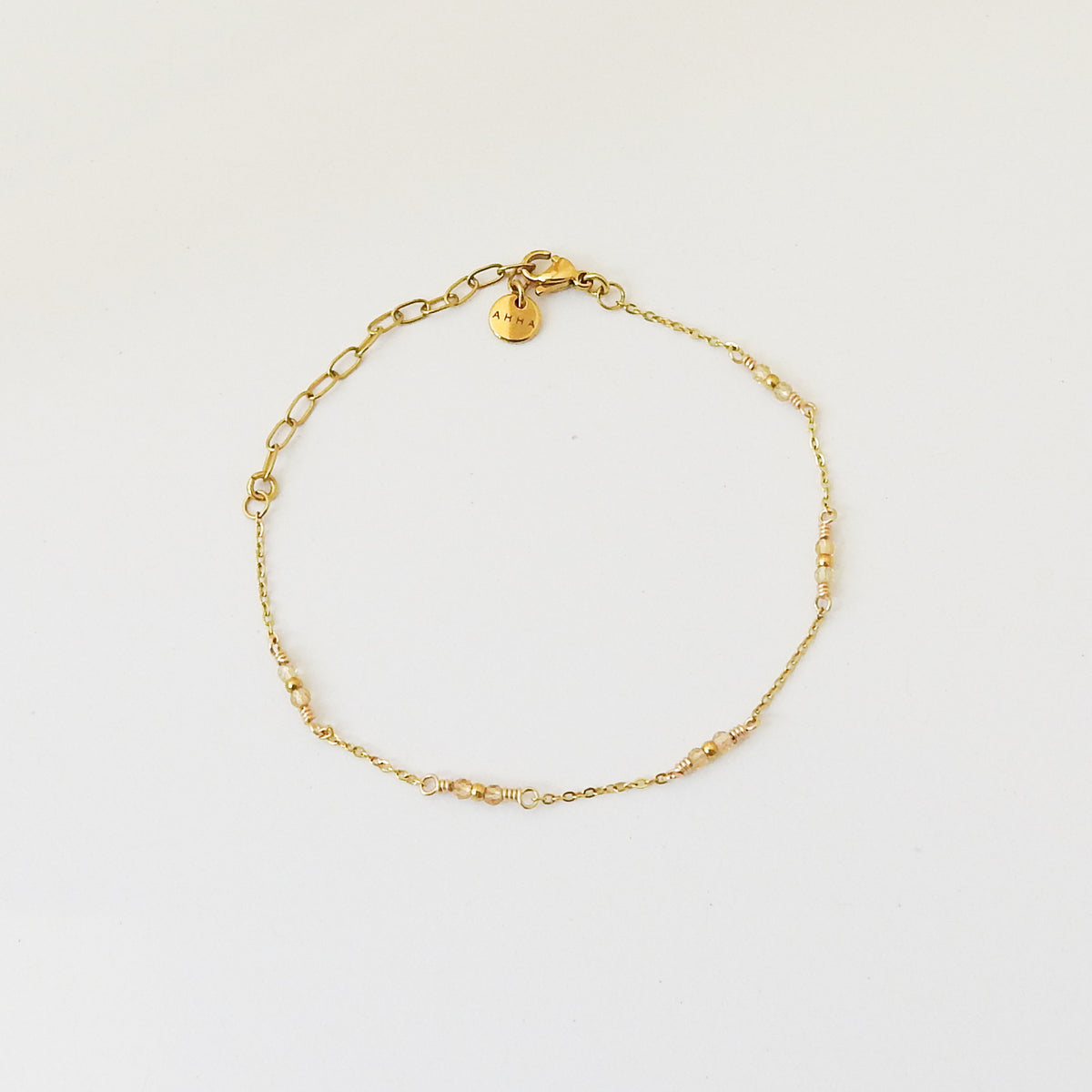 A delicate gold chain bracelet with small yellow bead accents and a lobster clasp, displayed on a clean white background.