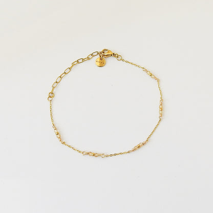 A delicate gold chain bracelet with small yellow bead accents and a lobster clasp, displayed on a clean white background.