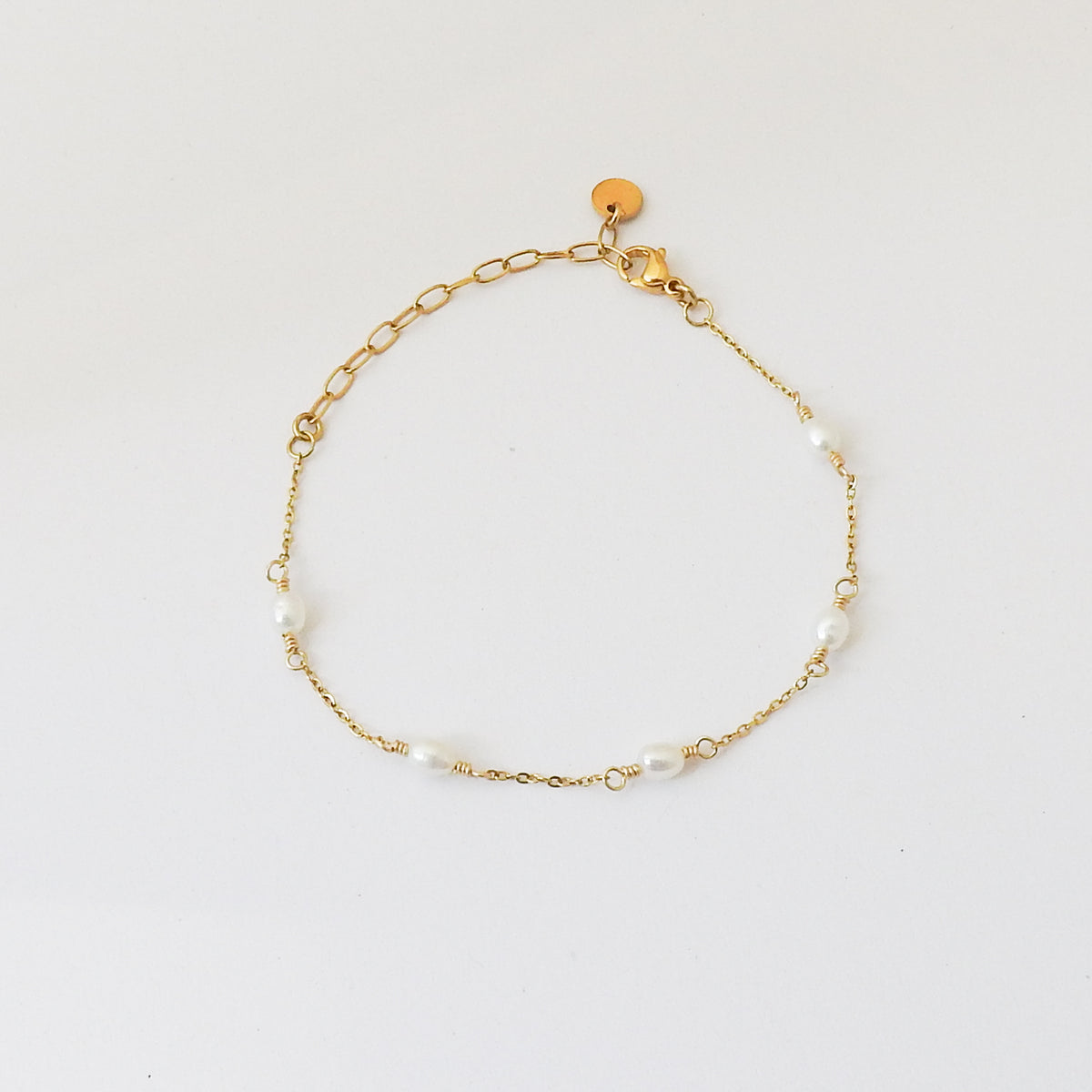 A delicate gold chain bracelet with irregular white pearl beads spaced along the chain, displayed on a clean white background.