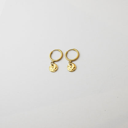 A pair of small gold hoop earrings with dangling textured round charms, displayed on a clean white background.
