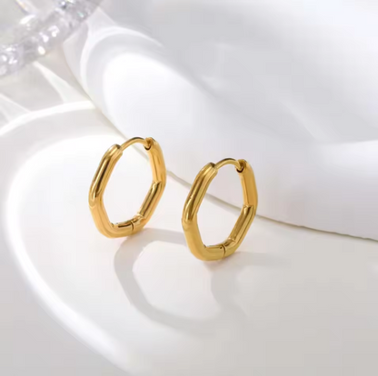 A pair of gold hoop earrings with a textured, segmented bamboo-like design, displayed on a clean white surface with soft shadows.