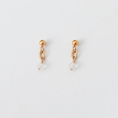 A pair of gold dangle earrings with a small clear faceted bead hanging from an openwork oval loop, shown on a plain white background.