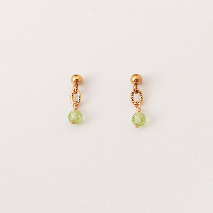 A pair of small gold dangle earrings with a faceted light green bead hanging from a delicate openwork loop, shown on a plain white background.