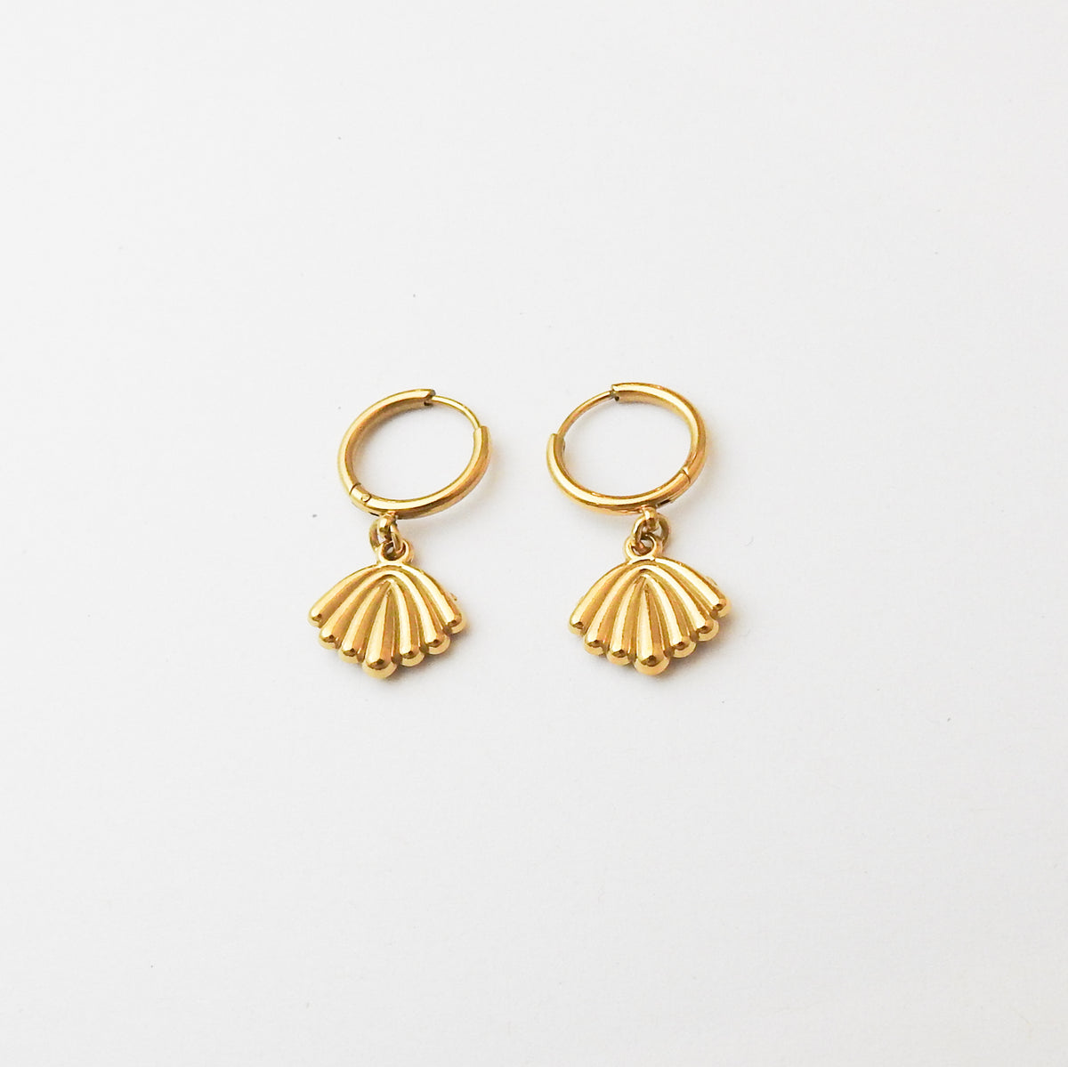 A pair of gold hoop earrings with dangling scallop-shaped charms, displayed on a clean white background.
