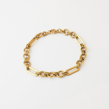 A gold paperclip chain bracelet with alternating oval and elongated links, displayed on a clean white background.
