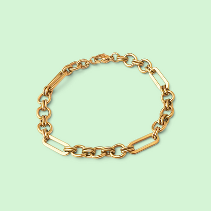 A gold-tone chain link bracelet with alternating oval and elongated links, arranged in a circle on a solid pale mint green background.