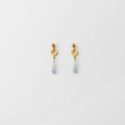 A pair of gold dangle earrings with a textured circular disc, a small gold bead, and three light blue beads hanging below, shown on a plain white background.