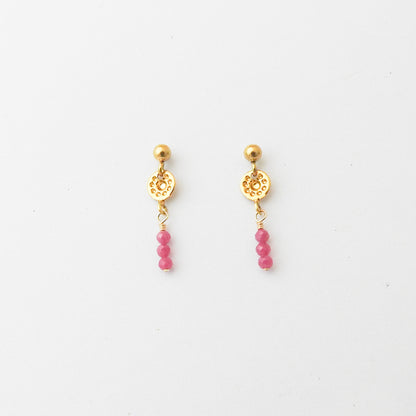 A pair of gold drop earrings with a textured circular disc, a small gold bead, and three dangling pink beads, shown on a plain white background.