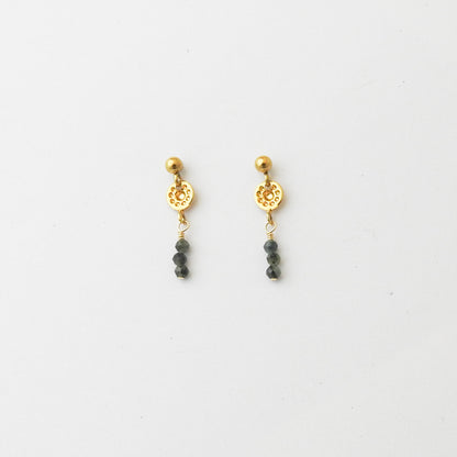 A pair of gold dangle earrings with a textured circular disc, a small gold bead, and three dark gray beads hanging below, displayed on a clean white background.