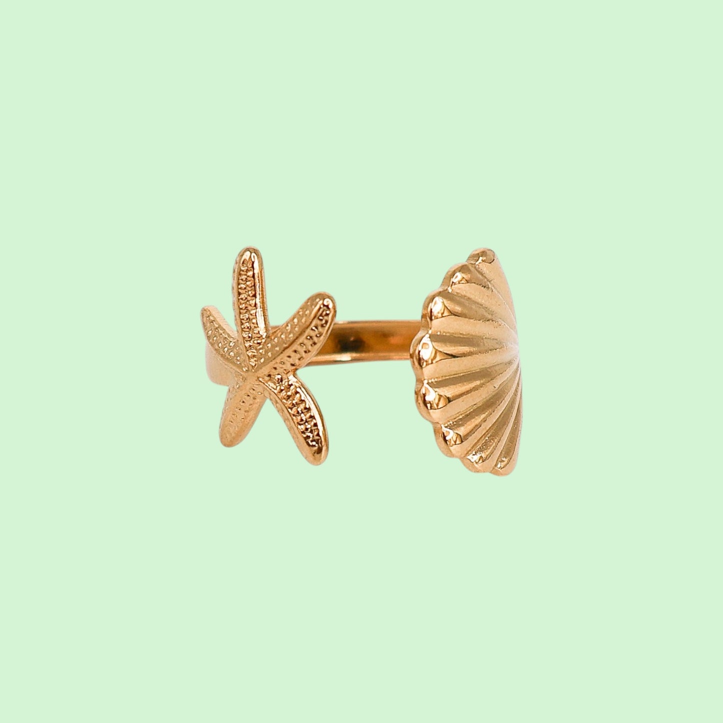 Gold starfish and shell ring on a light green background