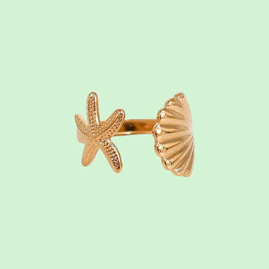 Gold starfish and shell ring on a light green background