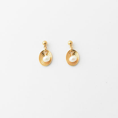 A pair of gold-toned dangle earrings with textured oval drops and white pearl-like center beads, shown on a plain white background.