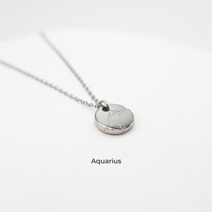 Silver necklace with a round pendant on a light gray background. The pendant is engraved with the Aquarius star sign constellation