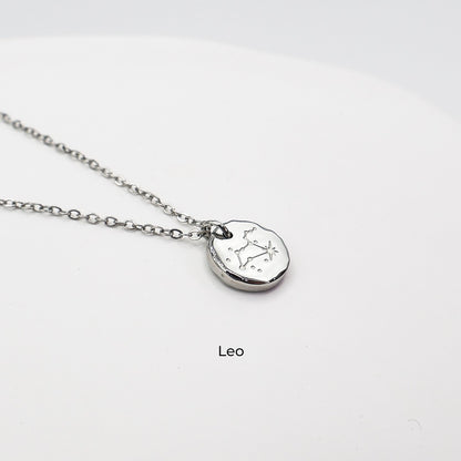Silver necklace with a round pendant on a light gray background. The pendant is engraved with the Leo star sign constellation