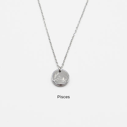 Silver necklace with a round pendant on a light gray background. The pendant is engraved with the Pisces star sign constellation