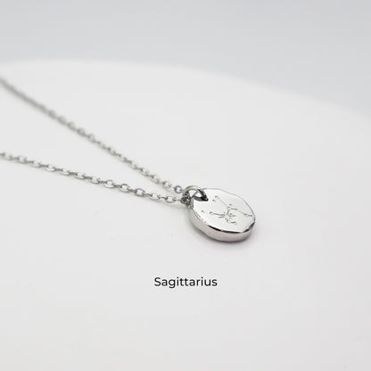 Silver necklace with a round pendant on a light gray background. The pendant is engraved with the Sagittarius star sign constellation