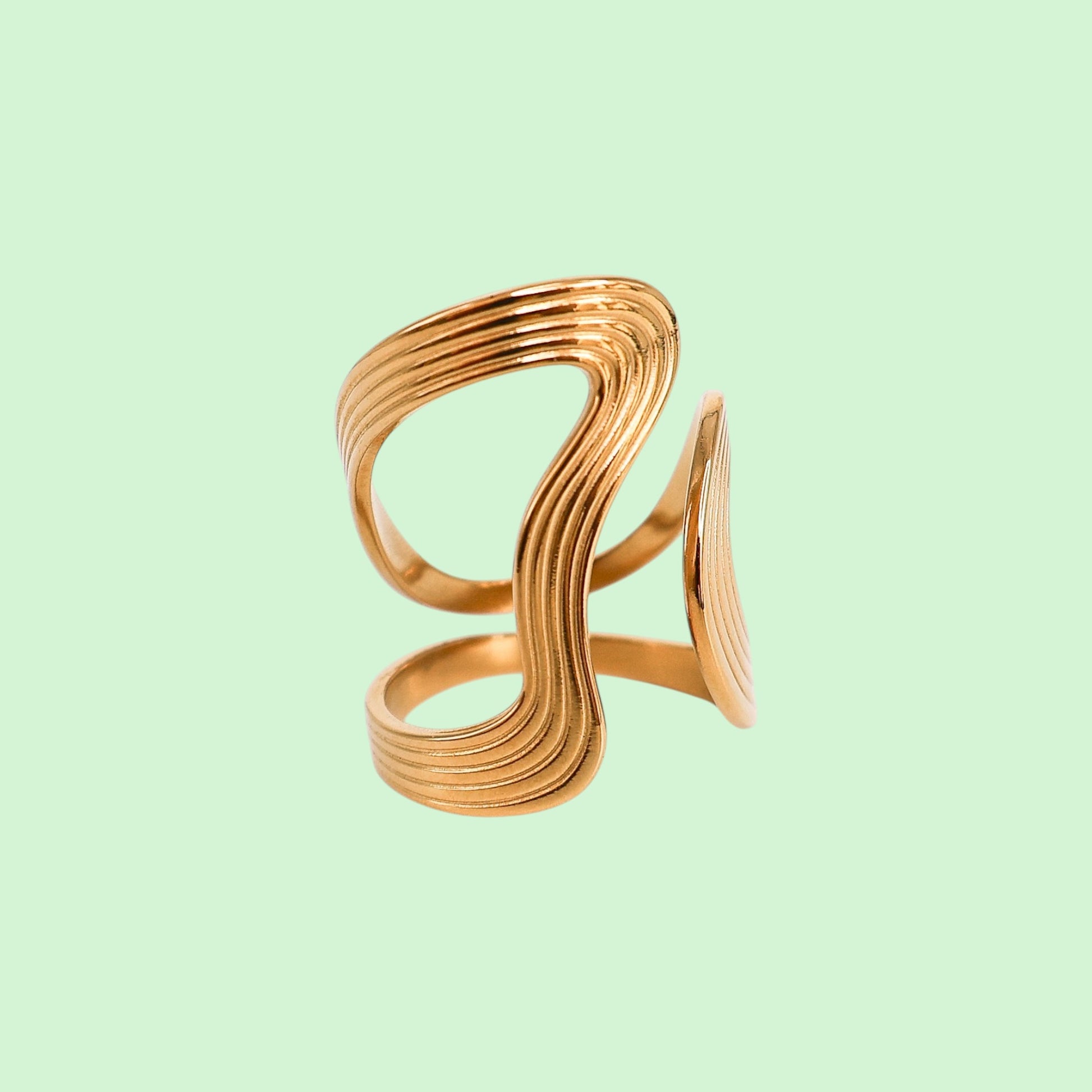 Gold spiral ring on a light green background